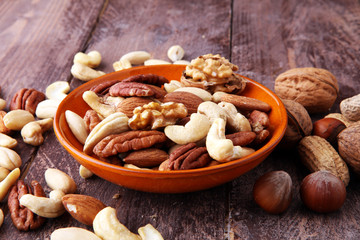 bowl with mixed nuts on wooden background. Healthy food and snack. Walnut, pecan, almonds, hazelnuts and cashews