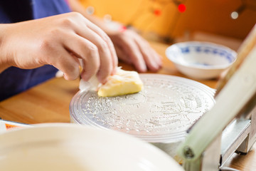 Traditional slovakian christmas wafer making machine. Female hands butter the machine surface.