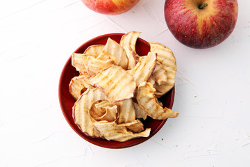 Fototapeta na wymiar Dehydrated apples chips in bowl and apples on white background.