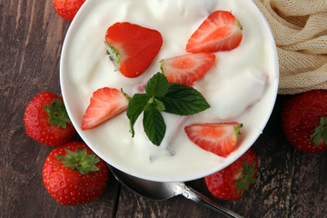Homemade yogurt with fresh strawberry on a wooden background.