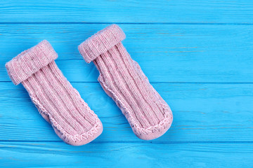 Baby wool socks on blue background. Pair of light pink baby-girl warm knitted socks on sale.