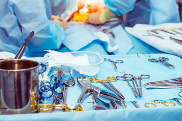 Close up surgical instruments and tools including scalpels, forceps and tweezers arranged on a table for a surgery. Selective focus.