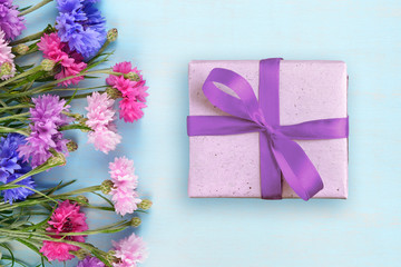 Cornflowers and gift box on blue background