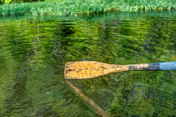 Closeup of oar paddle from row boat moving in water on green lake with ripples © Kristina Blokhin