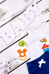 Baby boy high quality summer clothes. Infant boy casual cotton suit, pacifier, teether, old wooden background.
