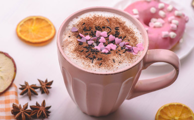rose mug of hot chocolate on the white table with rose donut and marshmallows.