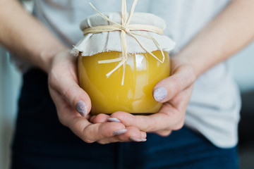 Close up of female hands holding a glass jar of organic honey