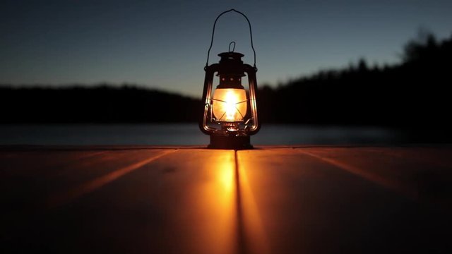 light from a kerosene lamp standing on a pier by the lake