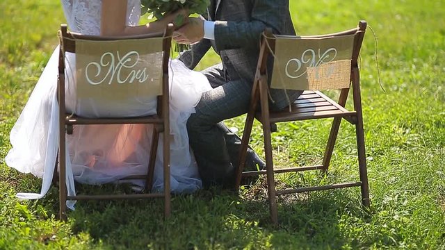 The bride and groom sit on chairs with the inscription Mr and Mrs.