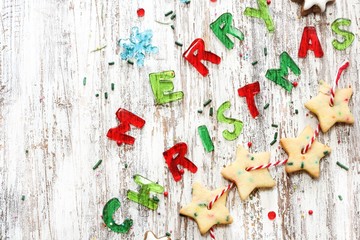 Merry Christmas message and homemade Xmas Garland cookies on rustic white wooden background