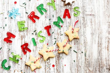 Merry Christmas message and homemade Xmas Garland cookies on rustic white wooden background