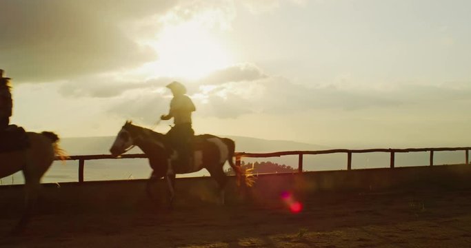 Couple horseback riding together at sunset