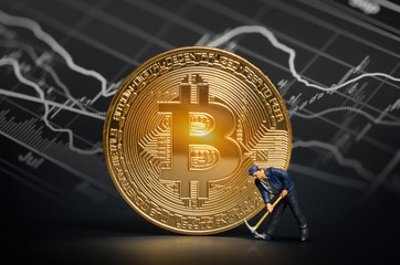 miner figurine with pickaxe and shiny bitcoin in front of bitcoin trading market data chart....