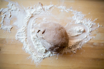 Solid ginger bread dough placed on a wooden board, in the kitchen on a table, view from above. Christmas baking at home concept. Selective focus