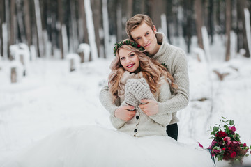 Newlyweds are hugging in the winter forest. Couple in love. Winter wedding ceremony.