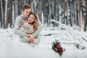 Bride and groom are hugging in the winter forest. Close-up. Winter wedding ceremony.