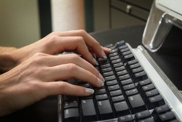 Woman's Hands Typing on Computer Keyboard. Closeup of a Woman's hands typing on a computer keyboard in an office or business situation.