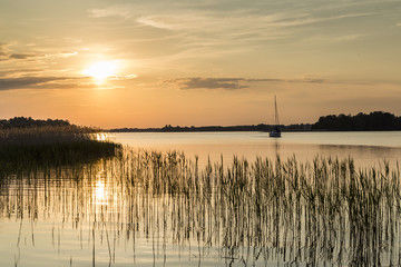 zdjęcie łódki w zachodzącym słońcu na jeziorze - obrazy, fototapety, plakaty