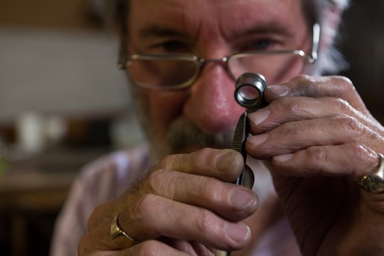 Goldsmith using magnifying glass in workshop