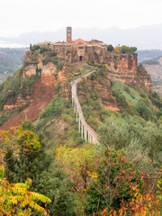 Obraz premium View of Civita de Bagnoregio from walkway with tourists during autumn season