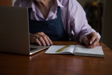 Goldsmith writing in book at desk