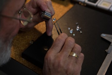 Goldsmith using magnifying glass in workshop