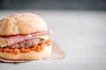 Beef burgers with ajvar and prosciutto,close up and blank space