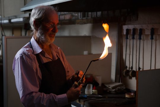 Goldsmith using welding torch in workshop