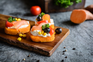 Sweet potato slices topped with cream cheese, smoked salmon, olives and corn