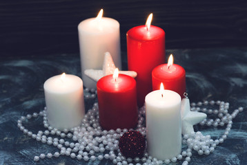 Fototapeta na wymiar Red and white candles,baubles and beads on a dark wooden background