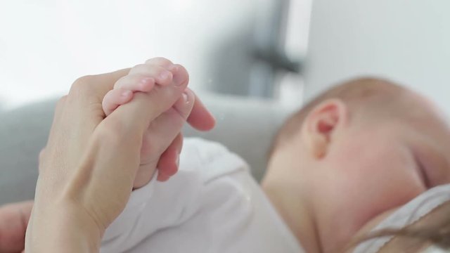 A parent holding the hand of a newborn baby, close up