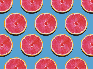 Grapefruit in flat lay Fruity pattern of grapefruit with red flesh on a blue background Top view Modern flat lay photo pattern in pop art style