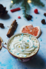 Homemade cocoa or hot chocolate, dried oranges, fir tree, cinnamon, candies on blue concrete background