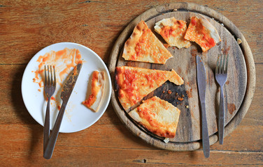 Piece of pizza remains on plate. Food waste.