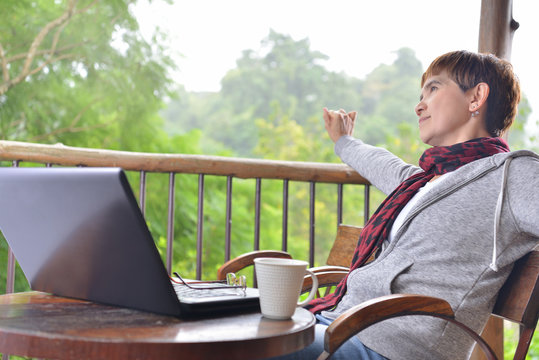 Happy middle age woman relaxing with laptop comper at home