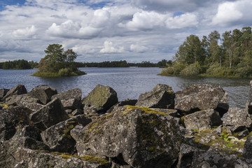 A wild lake with an island surrounded by wild forests - obrazy, fototapety, plakaty