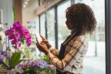 Female florist taking photograph of flower bouquet