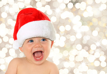 Happy ten month old blue eyed baby boy wearing a Christmas Santa hat. 