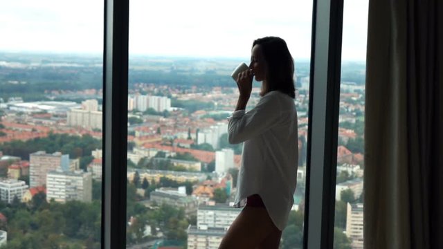 Woman drinking coffee and admire view from window, super slow motion 240fps

