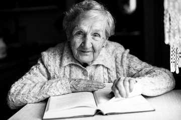 Elderly woman reading a book. Black-and-white photo.