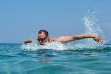 Tourist man in swimming sports glasses is floating in the Aegean Sea on the coast of Sithonia Peninsula