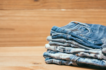 Fashionable clothes. pile of jeans on a wooden background