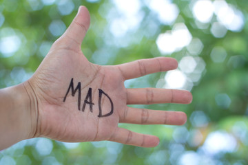 Concept Photo Of A Handwriting Word "MAD" On The Left Hand With Blurry Background