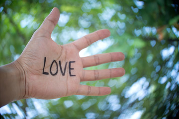 Concept Photo Of A Handwriting Word "LOVE" On The Left Hand With Blurry Background