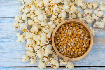 Obraz na płótnie Canvas wood bowl of popcorn on light blue wooden surface, popcorn snack with corn seed.