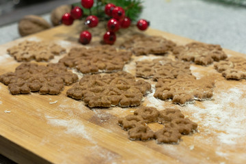 Christmas star-shaped cookies stacked on a wooden board crushed with flour sprinkled with green spruce and red cranberries