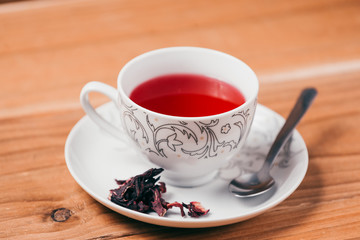 Red hot hibiscus tea in a glass mug on a wooden table