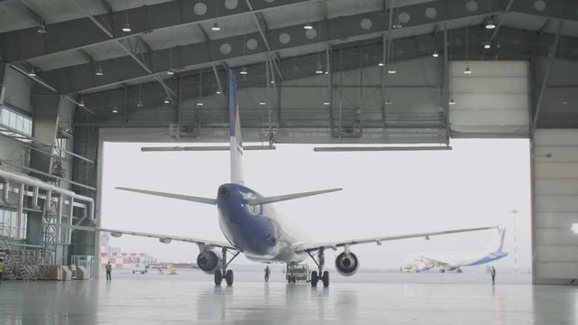 Passenger plane maintenance engines and fuselage repair leaves the hangar of the airport. Plane leaves the hangar after repairs