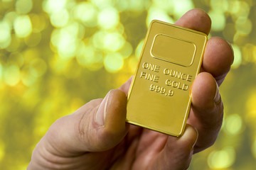 A small ingot of gold in the hand. One ounce of gold. Show gold.