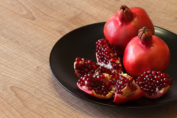 Ripe Azerbaijani pomegranate on a black plate and on a wooden table